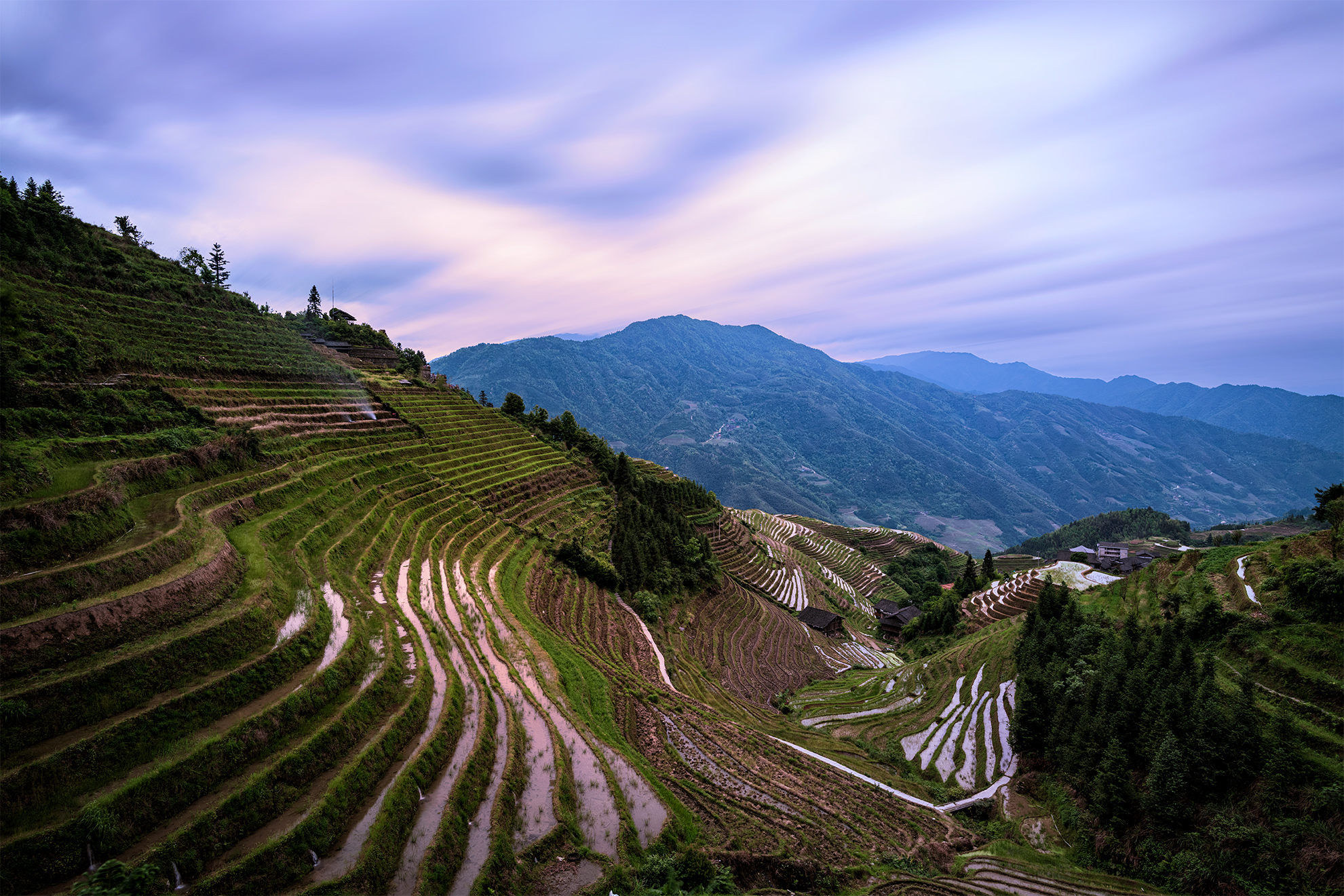 early evening clouds drift over the slopes of the Longji rice terrace mountains