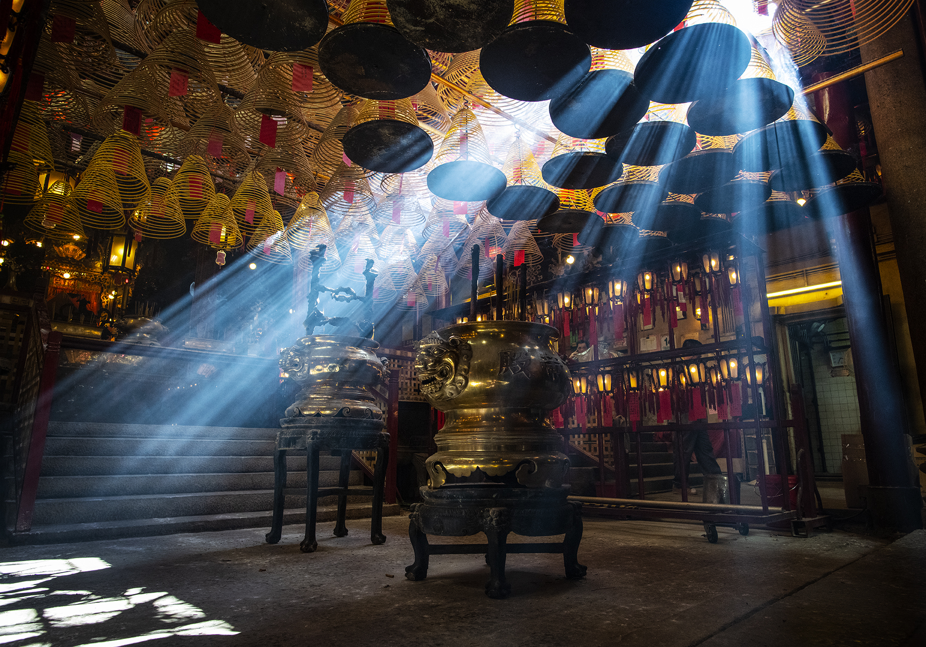 blades of light cut through the mist of Man Mo temple in Hong Kong