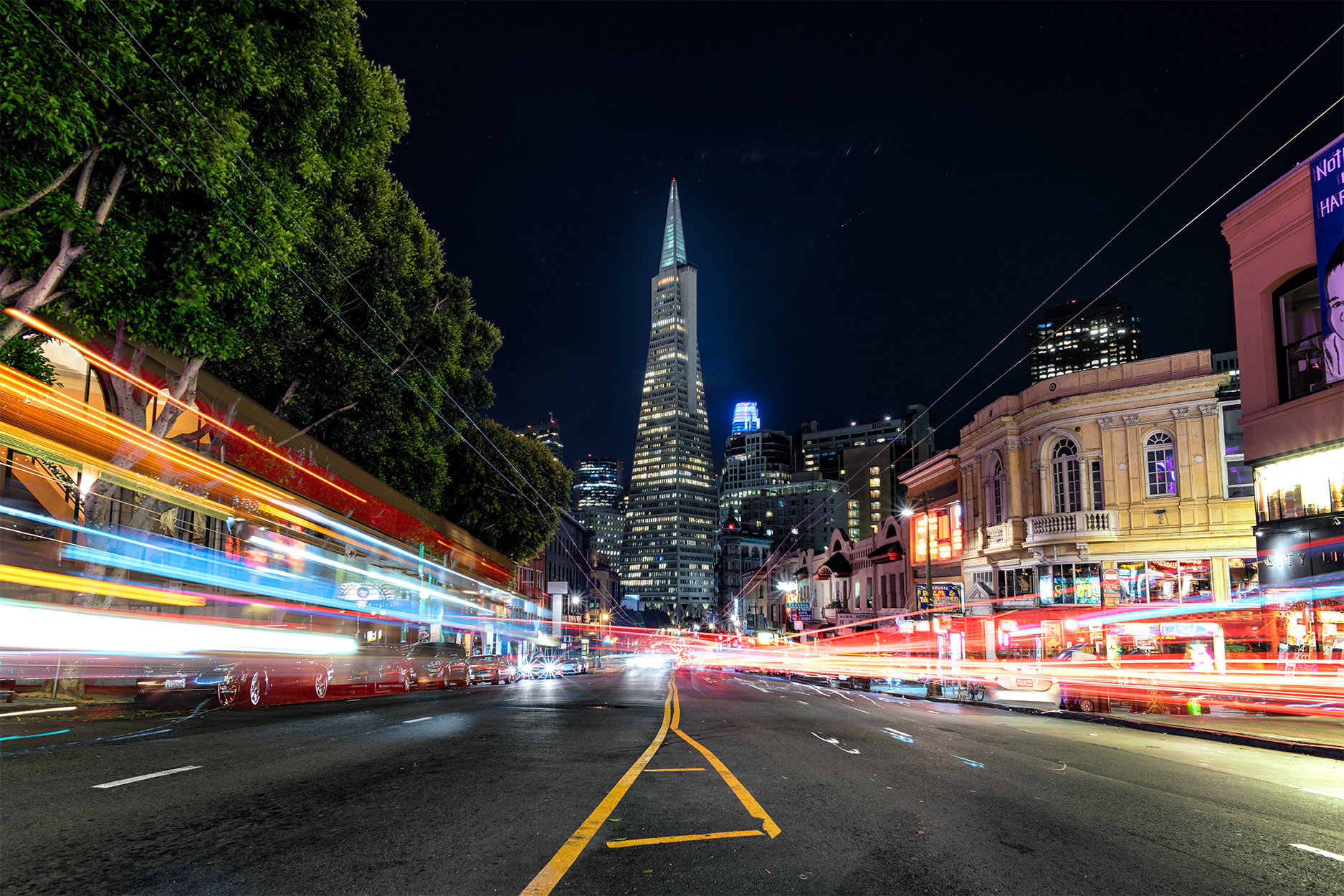 Long exposure light trails on either side, looking down the street toward the Transamerica Pyramid at night