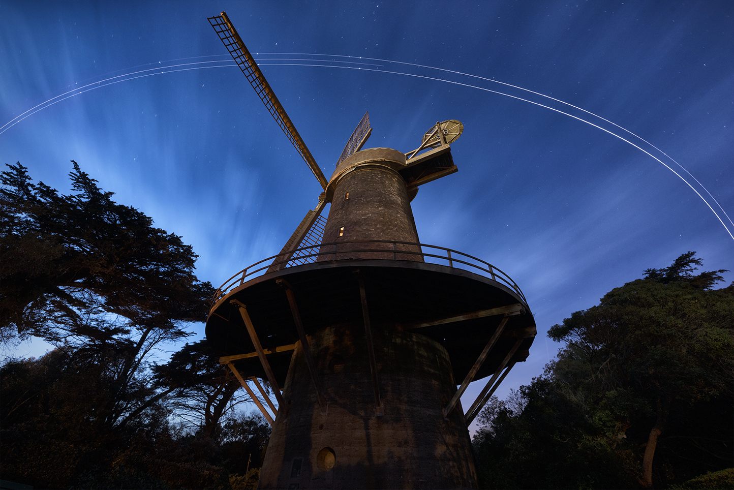 SF Dutch Windmill at evening blue hour as a plane cruises overhead