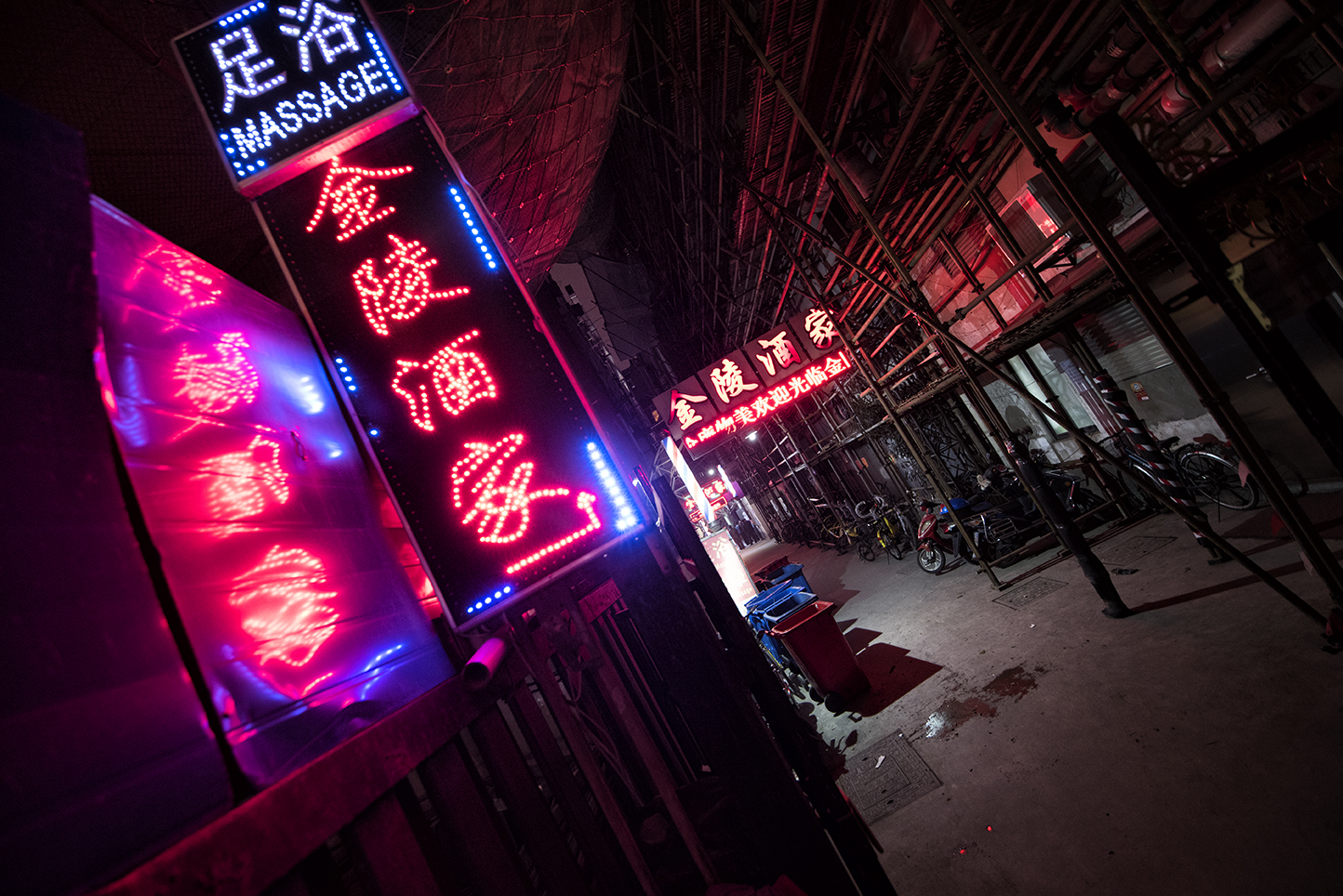 flickering neon lights from the darkness of one of the many busy alleys of Shanghai