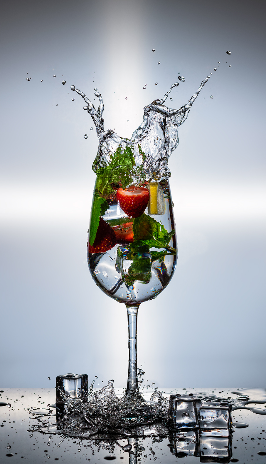 sparkling water and strawberries splash out of glassware